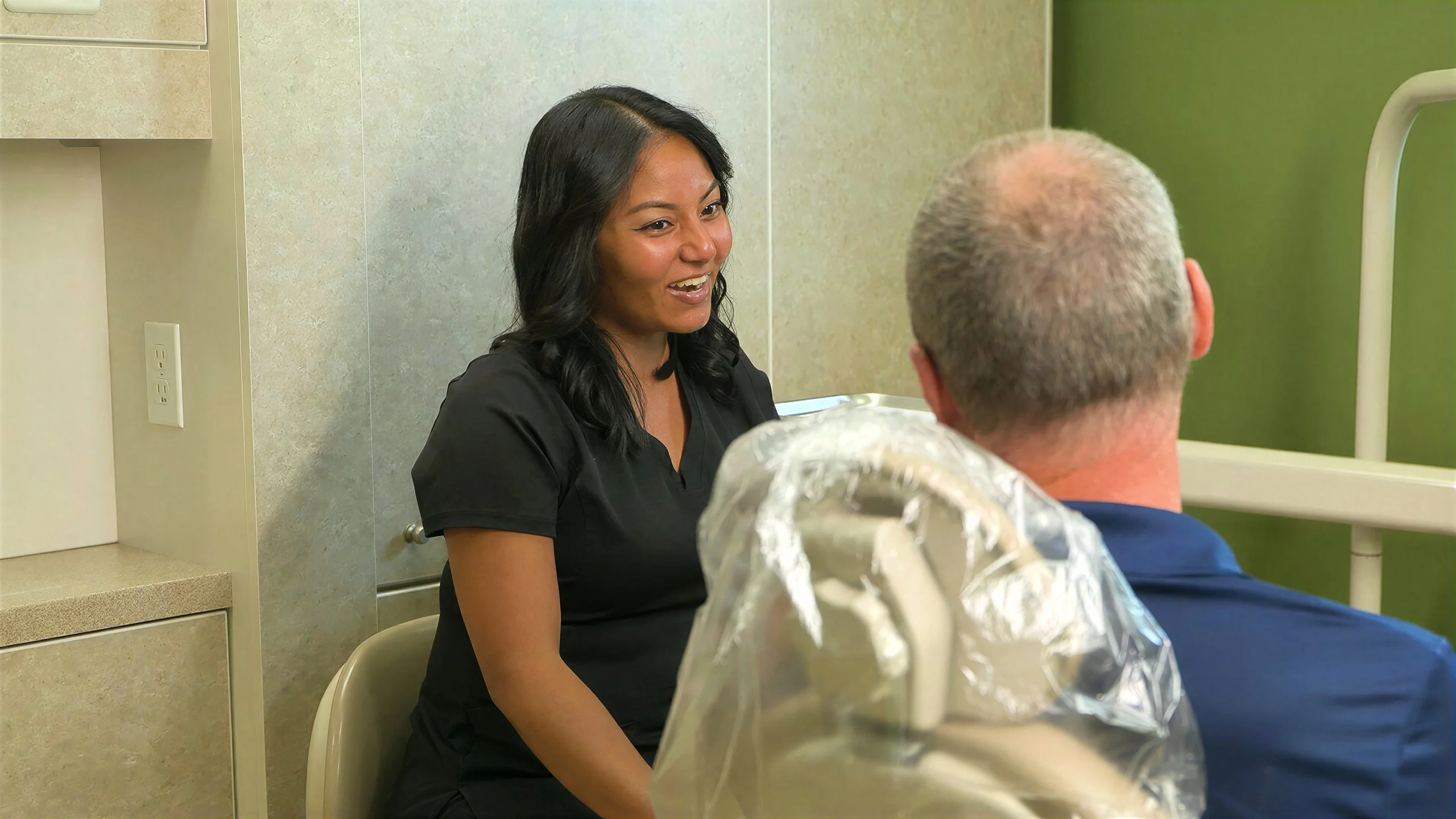 A Broadway Dentistry hygienist smiling as she talks with a patient in the chair before a cleaning in Fort Wayne